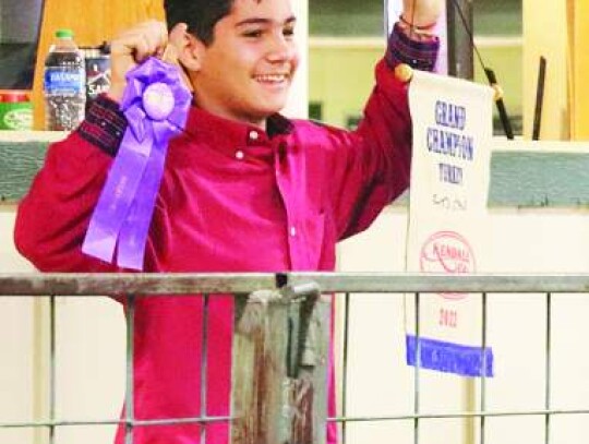 Simon Mecke-Lozano is all smiles as he shows off a ribbon and his grand champion banner for his prize turkey during Saturday’s Kendall County Junior Livestock Show Sale. Star photo by Zachary-Taylor Wright