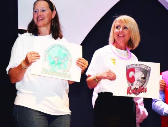 Van Raub and Kendall Elementary Principals Summer Gault and Jennifer Escamilla hold up school signs as they participate in a game. 