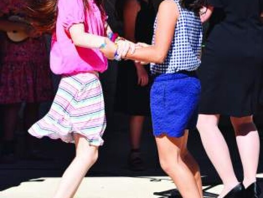 Fourth-graders Sunny Johnson and Ninelle Yefanova use a cellphone to take pictures of other CCES students before they enter the school. 