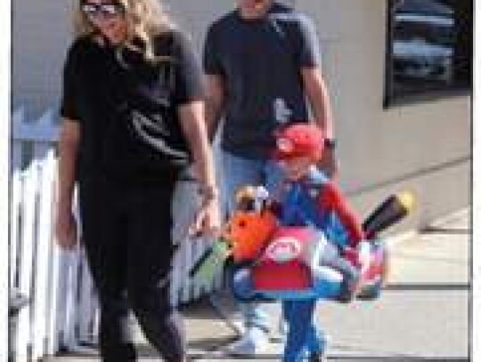 Natalie and Bryan lead Raymond down Main Street to gather candy in his Mario costume.