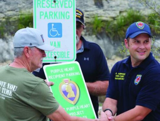 Bergheim VFD Chief Adam Hawkins is handed a new Purple Heart parking sign.