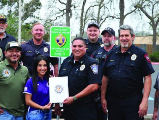 The Purple Heart Project volunteers and Boerne officers all gather around in celebration of the new parking sign dedicated for Purple Heart recipients at the Boerne police station Tuesday afternoon.