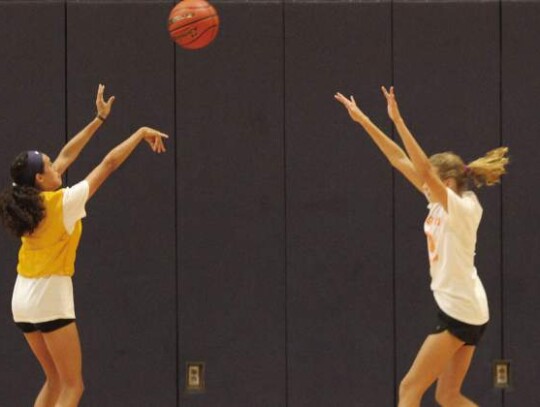 One of the young ladies launches a shot as another defends.