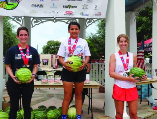 Watermelons were handed to the top three finishers in each age division of the Flag Run 5K. In the women’s 30-30 age group, Paola Gutierrez (center) won with a time of 24:24, with Chelsea Tieken (left) placing second and Emily Cardenas taking third.