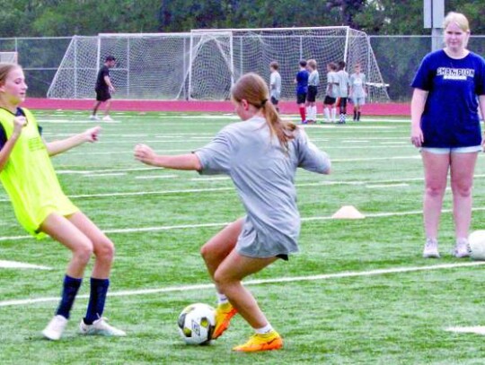 New Champion girls soccer coach Alyse Zingelmann watches as campers go through a drill, while in the background, BHS boys soccer coach Michael Strong works with some of the campers on another drill.