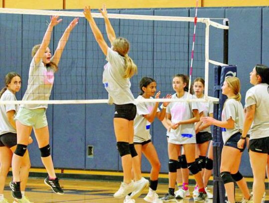 Boerne High assistant volleyball coach Allison Bendas works with campers on a blocking drill at the net.