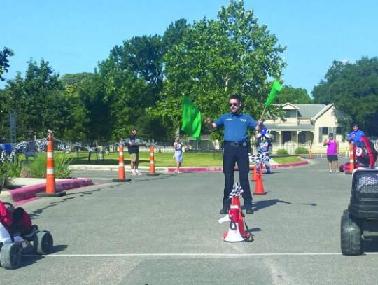 Boerne Police Department’s Christopher Dingman gives the green flag to two racers during the Kids Powerwheels Drag Race July 15. Photos by Xochilt Garcia