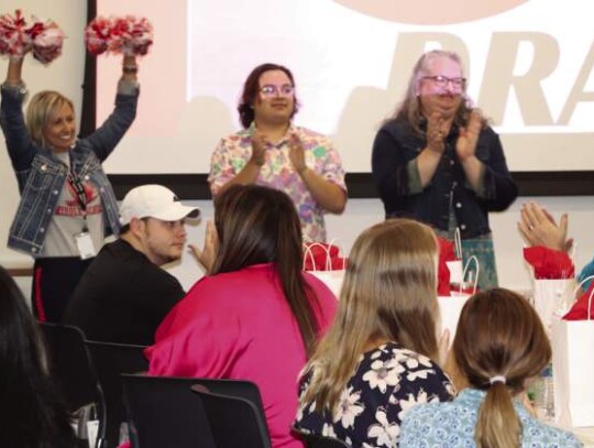 Voss Middle School Principal Kathy Cornett vigorously shakes pom-poms in her school’s colors Monday during Boerne ISD’s new teacher introductions.