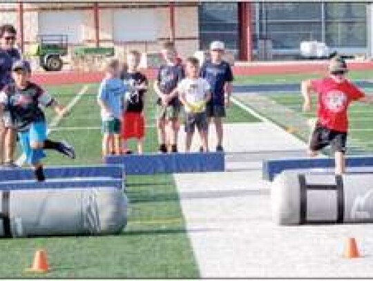 Champion assistant football coach Chris Troilo supervises as the young men go through a footwork drill at the camp.