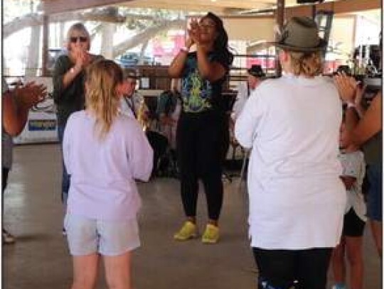 Brandy Jarrett, center, claps while joining a circle of fair attendees doing “The Chicken Dance” when played by the Boerne Village Band.