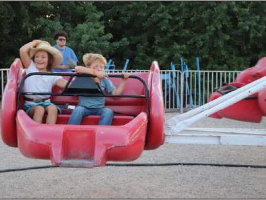 Aeralen Van Dyke, 7, holds on to her hat as she and Mason Reichenau, 6, get tossed to and fro on The Sizzler, one of the carnival rides at the fair.