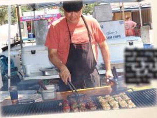 Ace Carter turns beef and chicken kabobs Sunday while helping out at A Little Taste of Heaven’s booth at the Kendall County Fair.